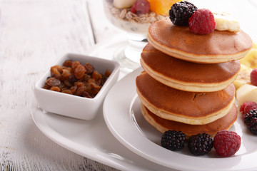 Pancake with fruits and muesli on plate on table close up