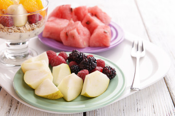 Slices of fruits with berries and muesli on wooden table