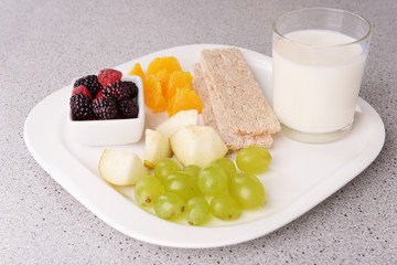 Slices of fruits with crispbreads and glass of milk