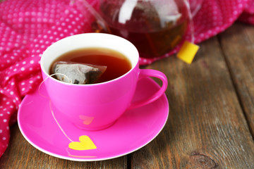 Cup of tea, teapot and tea bags on wooden table close-up
