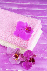 Obraz na płótnie Canvas Orchid flowers and towels on color wooden background