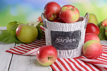 Sweet apples in basket on table on bright background