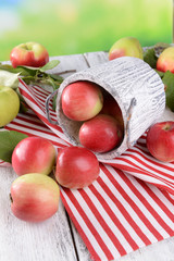 Sweet apples in basket on table on bright background