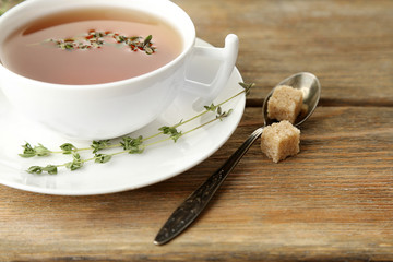 Cup of tasty herbal tea with thyme on wooden table