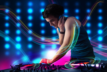 Young Dj mixing records with colorful lights