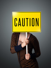 Young woman holding a caution sign