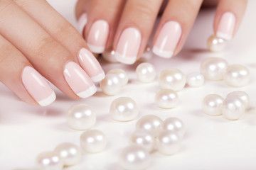 Beautiful woman's nails with french manicure and pearls.