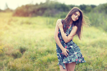 Naklejka na ściany i meble beautiful brunette in a field on a sunny day