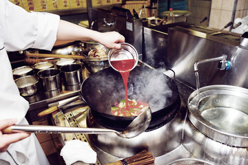 Chef is pouring sour sauce in wok