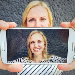 Fotobehang Mädchen macht Selfie mit Smartphone © Robert Kneschke