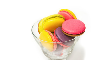 Colorful macaroons in cocktail glass on white background