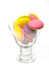 Colorful macaroons in cocktail glass on white background