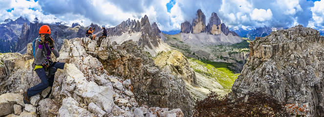 Young woman taking a photo on one of the peaks of the Dolomites