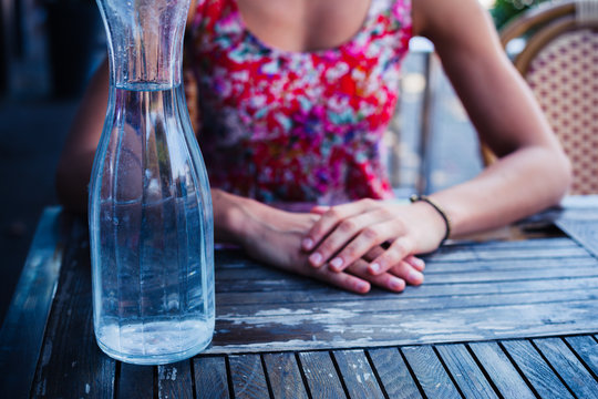 Woman sitting at table with jug of water