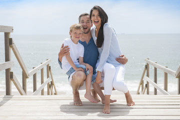 happy family  standing on a wood pontoon in front of the sea in