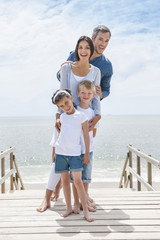 happy family  standing on a wood pontoon in front of the sea in