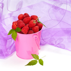 Raspberries in a small pink metal bucket. Selective focus.