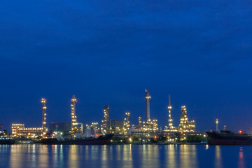 Obraz na płótnie Canvas Oil refinery beside a river during twilight