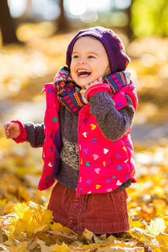 Happy little girl playing in the autumn park