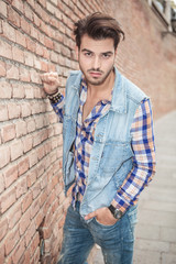 man posing for the camera near a brick wall