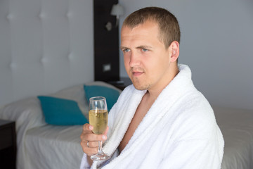 happy man in bathrobe drinking champagne in hotel room