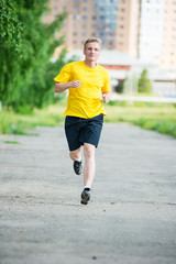 Sporty man jogging in city street park. Outdoor fitness.