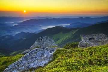Fototapety  Trawa i kamienie na górskim wzgórzu podczas zachodu słońca