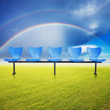 chairs over the grass filed and rainbow background