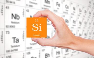 Silicon symbol handheld in front of the periodic table
