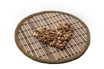 Selbstklebende Fototapeten Heart of coffee beans on a round matting isolated © angor75