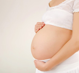 Closeup on pregnant belly.Woman expecting baby dressed in white.