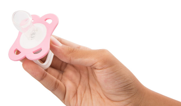 Female hand holding pink pacifier over white background