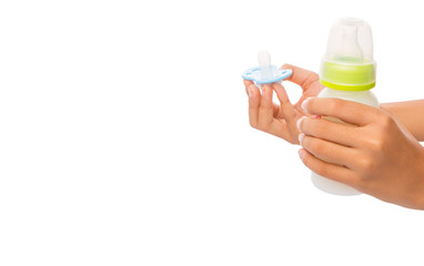 Female hand holding a pink pacifier with a bottle of baby's milk