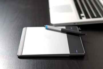Graphic tablet on the table with notebook.
