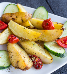 baked potato and raw vegetables on a white plate, closeup
