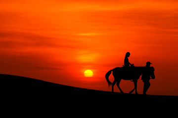 Obraz na płótnie Canvas sillhouette of a journey on horseback with sunset