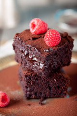 Brownies with raspberry on a wooden background.