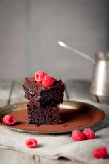 Brownies with raspberry on a wooden background.