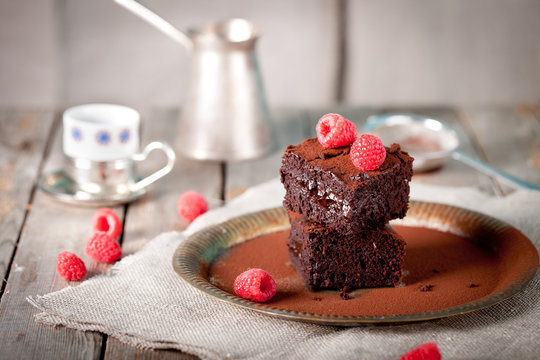 Brownies with raspberry on a wooden background.