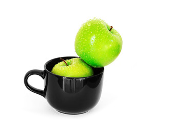 fresh green apple in black ceramic cup on white background