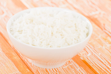 Steamed Rice - Boiled rice in a bowl on an orange background.