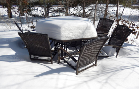 Backyard patio and outdoor furniture covered in winter snow