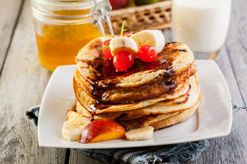 Pancakes with chocolate sauce fruit and glass of milk