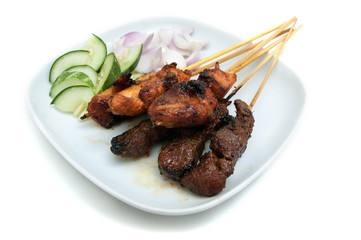 Delicious satay with cucumbers and onions served on white plate