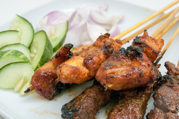 Delicious satay with cucumbers and onions served on white plate
