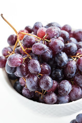 Dark grape in a bowl on white