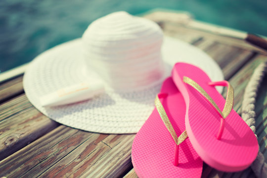 close up of hat, sunscreen and slippers at seaside