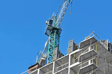 Crane and building construction site against blue sky