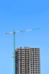 Crane and building construction site against blue sky