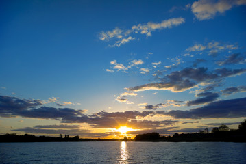 Obraz na płótnie Canvas Sunset over the lake on a background of blue sky